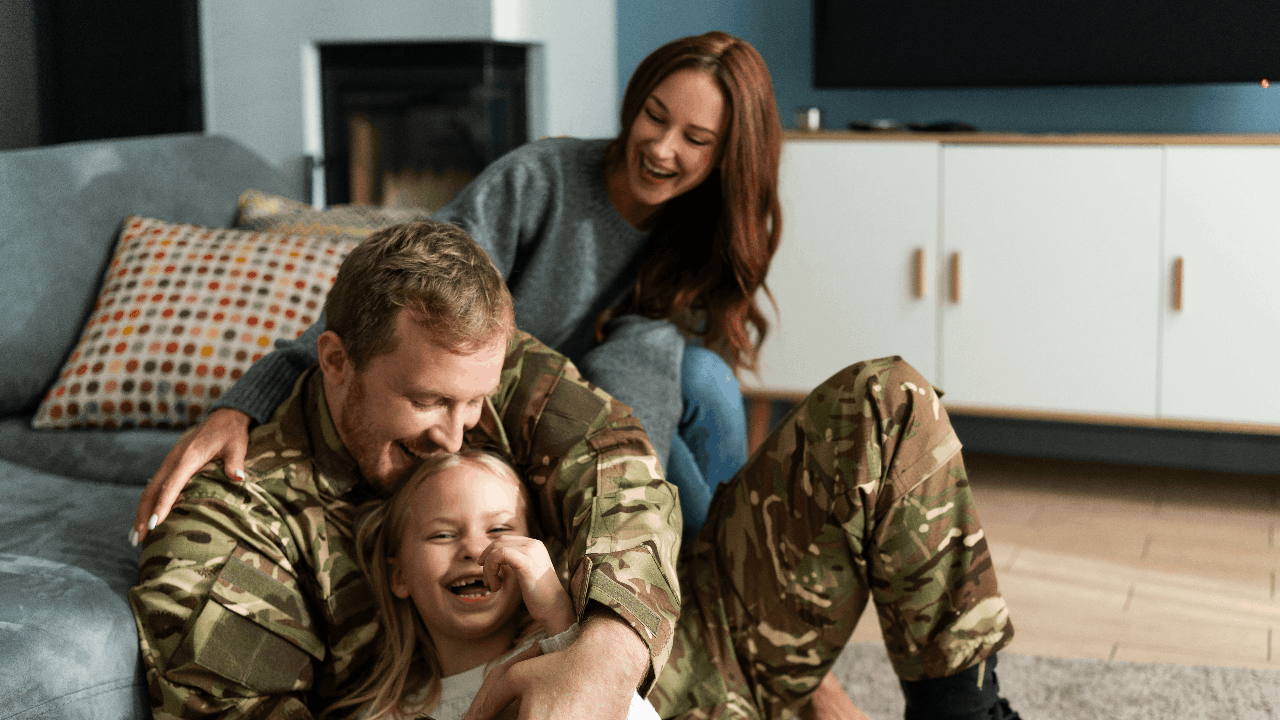 Overjoyed soldier tickling small daughter while sitting at home